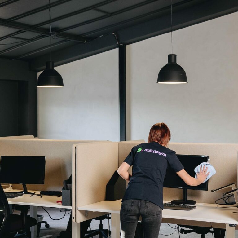 Kontorsstädning - kvinna rengör skrivbord